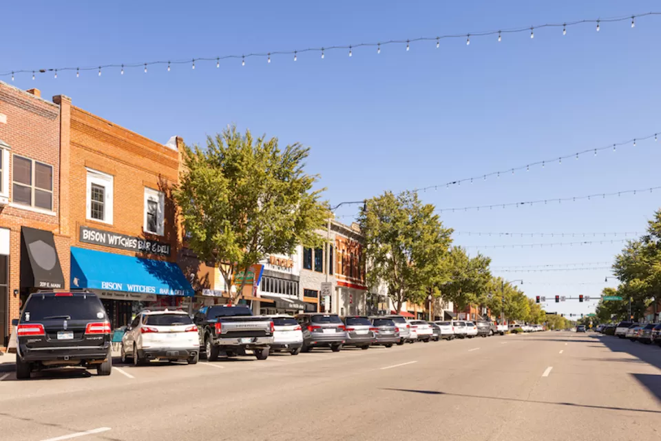 View of small-town street with brick buildings and cars parked in diagonal parking with string lights going across street in Cleveland County, Oklahoma.